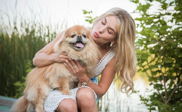 Bella donna bionda con il suo cane su un lago, concetto di amore per gli animali domestici. Amicizia umana e animale - Foto, immagini