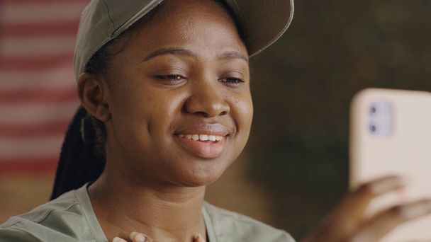Glückliche schwarze Soldatin diskutiert Nachrichten mit Online-Freund - Foto, Bild