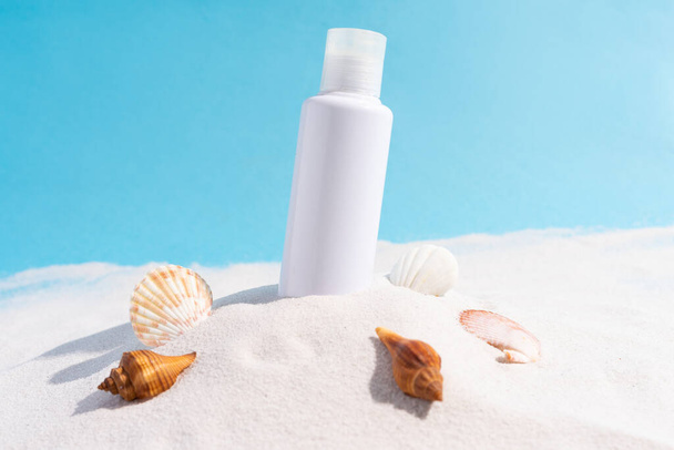 The cosmetic bottle is stuck on the sand with seashells around it - Foto, Imagem