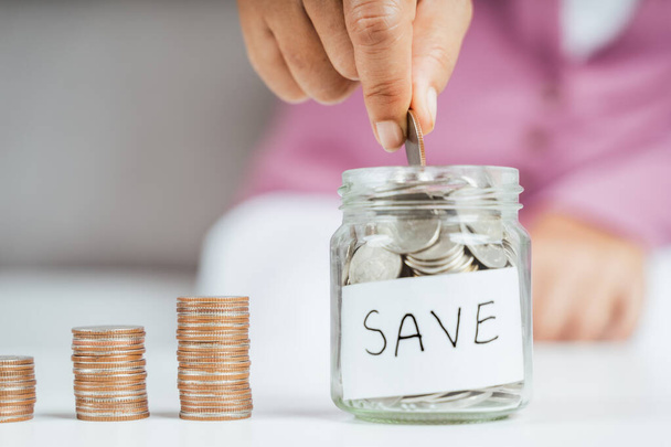 women hand putting money coin into glass jar for saving money. saving money and financial concept - Foto, immagini