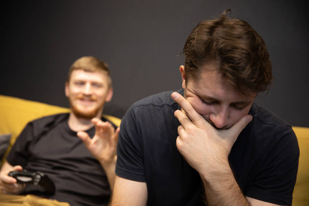 gamer covered his face with palm. Smiling opponent comforts video game loser - Photo, Image