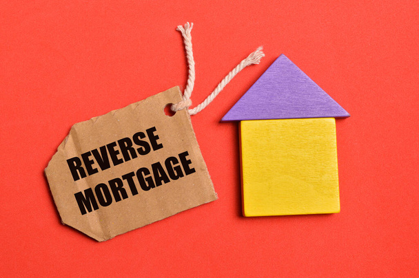 Oyuncak ev ve etiket üst görünümü REVERSE MortGage ile yazılmış. Emlak kavramı. - Fotoğraf, Görsel