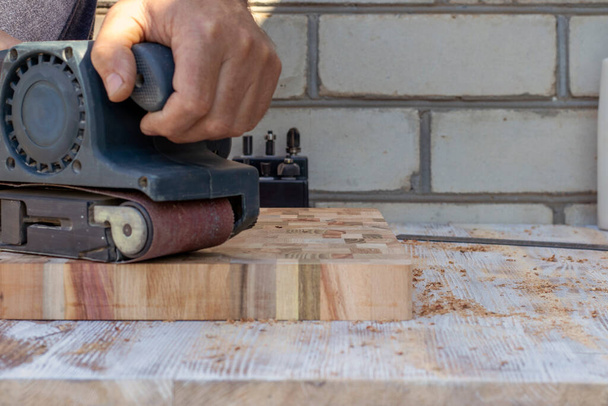 Плотник с ручной шлифовкой работает с куском дерева. - Фото, изображение
