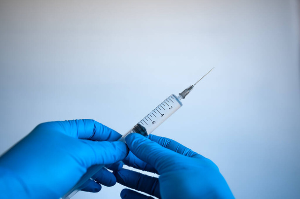Руки в голубых перчатках держат шприц с вакциной - Фото, изображение