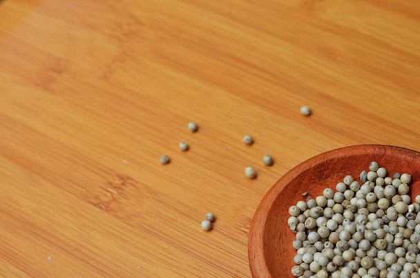 pepper in a wooden bowl on a wooden tray. close up with selective focus - Photo, Image