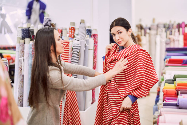Drapery mağaza sahibi kadın müşteriye tekstil kumaşı tavsiye ediyor - Fotoğraf, Görsel