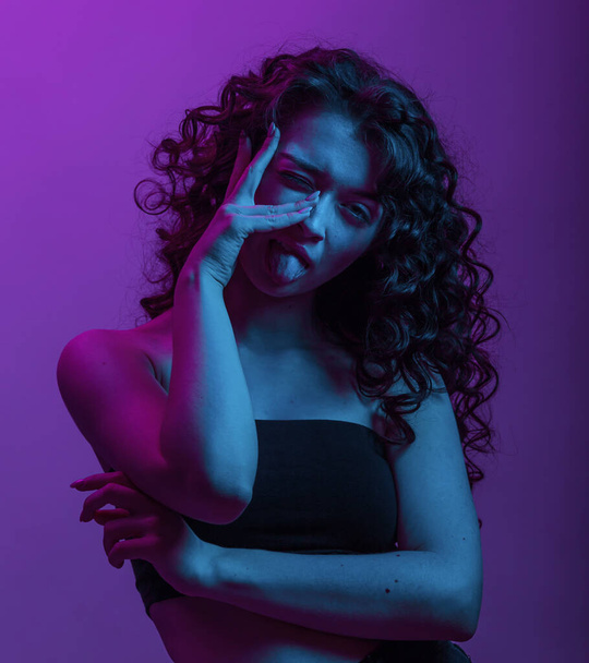 High fashion hair curling model woman in colorful bright neon UV blue and purple lights, posing in studio , beautiful, glowing makeup, colorful. - Zdjęcie, obraz