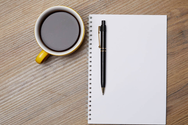 Notebook on table with pen and cup of coffee - Photo, Image