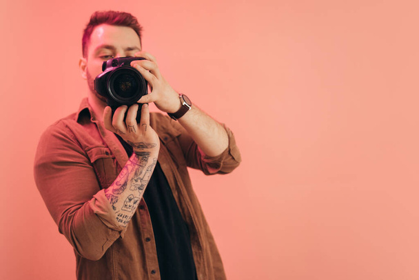 Photographer with digital photo camera at his hands posing in photo studio - Foto, Bild