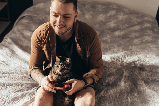 Man spending time with his striped cat at the cozy home atmosphere while playing - Foto, Imagem