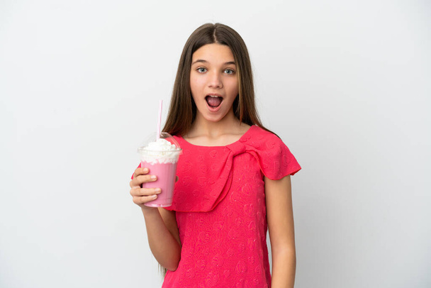 Dziewczynka z truskawkowym shake 'iem na białym tle z zaskakującym wyrazem twarzy - Zdjęcie, obraz