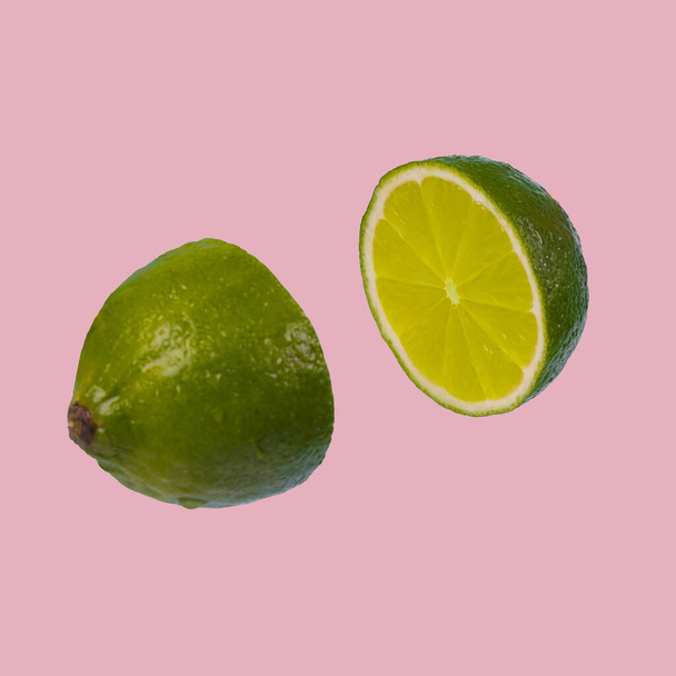 Minimal idea with fresh lime sliced on pastel pink background. Minimal fruit concept.Vitamins, healthy diet concept. Sliced lime floating in the air. Creative concept with flying fruits. - Photo, Image