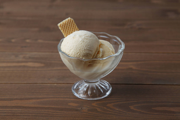 ice cream with wafer on dessert glass isolated on wooden table - Foto, Imagen
