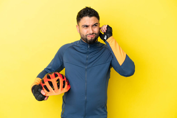 Young cyclist arab man isolated on yellow background frustrated and covering ears - Valokuva, kuva