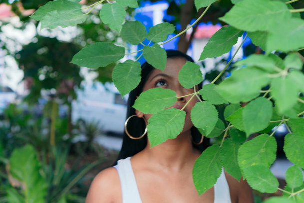Portrait of a pretty girl covering her face with green leaves. - Photo, Image