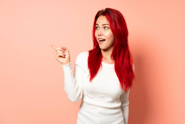 Teini punaiset hiukset tyttö eristetty vaaleanpunainen tausta aikoo tajuaa ratkaisun nostaessaan sormea ylös - Valokuva, kuva
