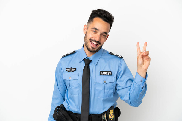 Police caucasien homme isolé sur fond blanc souriant et montrant signe de victoire - Photo, image