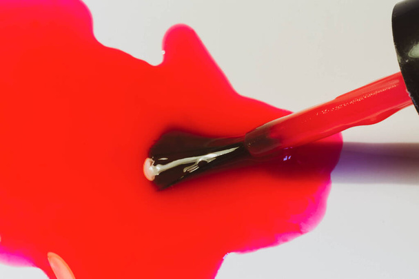 Rosa, smalto rosso partenza dalla bottiglia, pennello per l'applicazione di smalto sulle unghie primo piano. - Foto, immagini