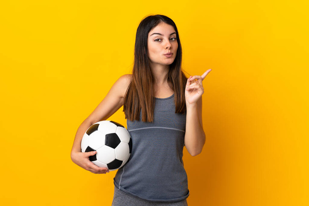 Jonge voetballer vrouw geïsoleerd op gele achtergrond van plan om de oplossing te realiseren, terwijl het opheffen van een vinger omhoog - Foto, afbeelding