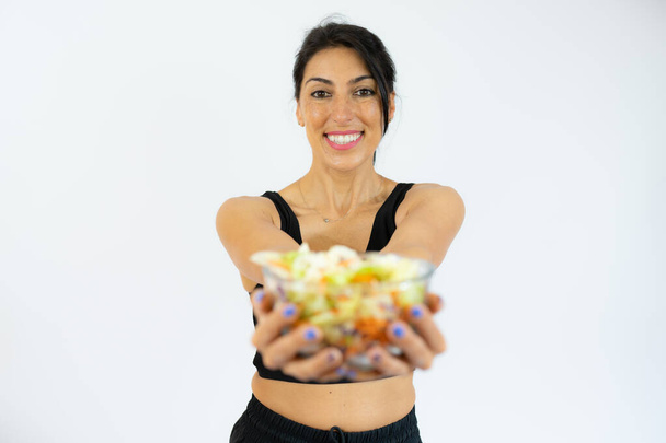 Profil portret pozytywna zdrowa kobieta w białej odzieży sportowej gospodarstwa duża miska ze świeżych sałatek warzywnych. Zdrowe odżywianie. - Zdjęcie, obraz
