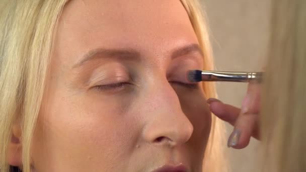 Ένας πελάτης σε κομμωτήριο βάφεται. make-up καλλιτέχνης κάνει σκιά ματιών - Πλάνα, βίντεο