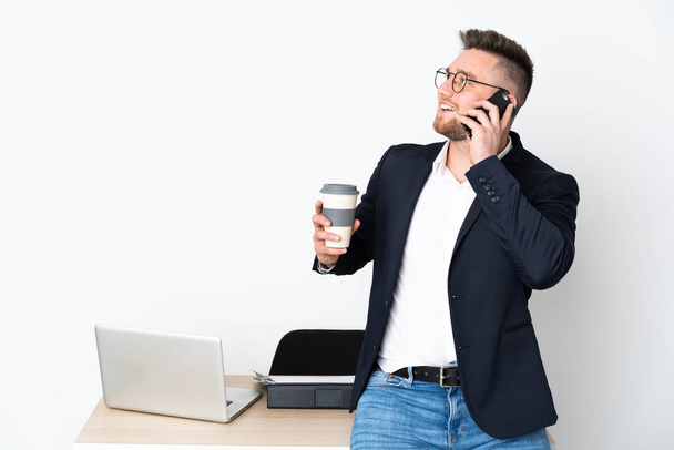 ロシア人男性でオフィスに隔離された白い背景にコーヒーを持ち去るために携帯電話 - 写真・画像