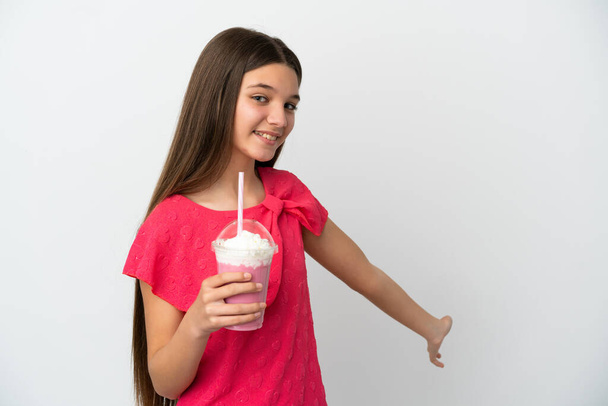 Маленька дівчинка з полуничним молочним коктейлем над ізольованим білим тлом, що розтягує руки на бік, щоб запросити прийти
 - Фото, зображення