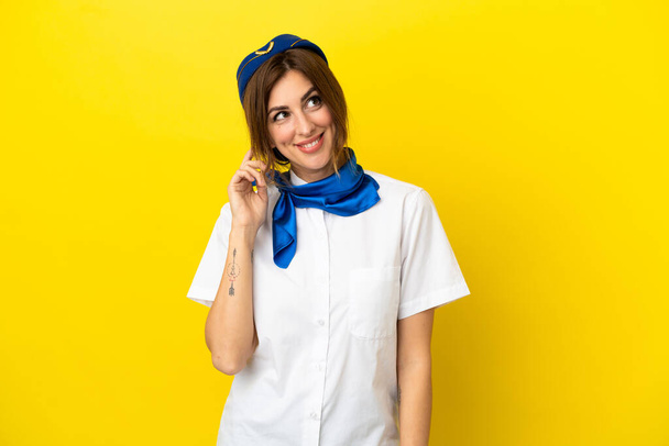 Airplane stewardess woman isolated on yellow background thinking an idea - Foto, Imagen