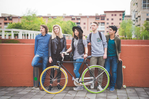 Gruppo di amici multietnici in posa all'aperto con skateboard e bicicletta godendo di trasporto sostenibile verde - Foto, immagini
