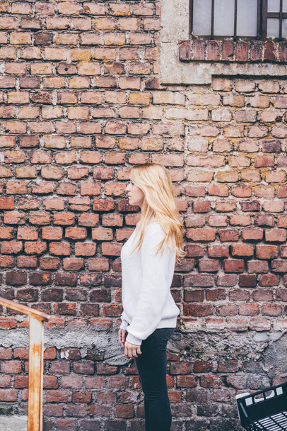 Young woman posing brick wall profile looking away pensive - Zdjęcie, obraz