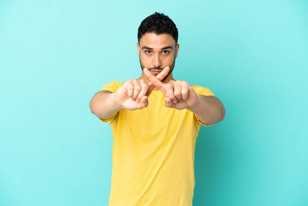 Молодий арабський чоловік ізольований на синьому фоні робить зупинити жест рукою, щоб зупинити акт
 - Фото, зображення