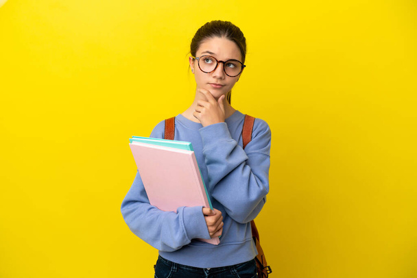 Student kid vrouw over geïsoleerde gele achtergrond met twijfels - Foto, afbeelding