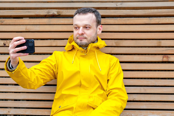 a man sitting relaxed outside and looking calmly at the phone - Photo, Image