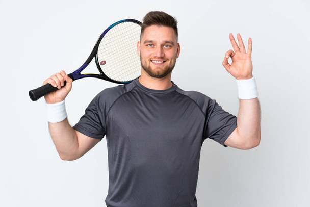 Russisch gut aussehender Mann isoliert auf weißem Hintergrund Tennis spielen und machen OK Zeichen - Foto, Bild