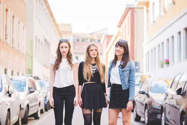 Tres jóvenes hermosas mujeres caucásicas millennials posando al aire libre en la ciudad, sonriendo - Foto, Imagen