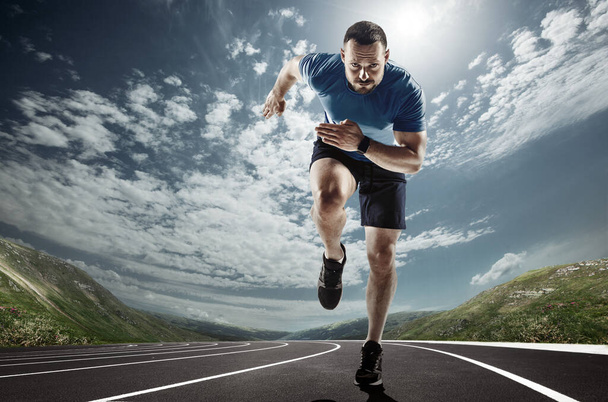 Professional male runner, jogger on road and sky background. Caucasian fit athlete practicing, training excited - Foto, Imagem
