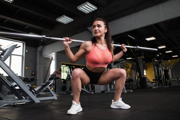 Low angle shot of a female bodybuilder exercising with barbell - Photo, Image