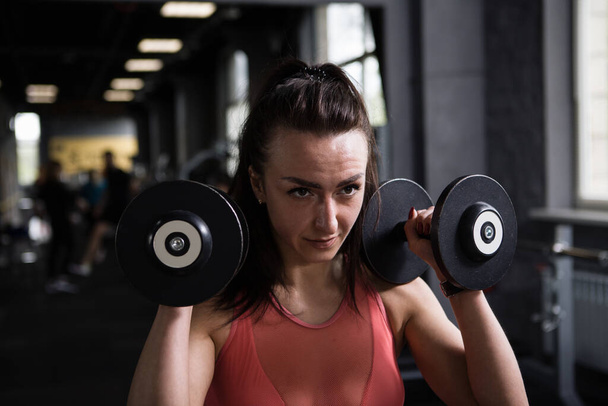 Close up of a focused female athlete exercising with dumbbells - Foto, Imagem