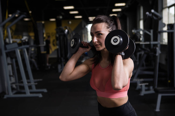 Mujer de fitness haciendo ejercicio con pesas en el gimnasio de entrenamiento funcional, espacio para copiar - Foto, imagen