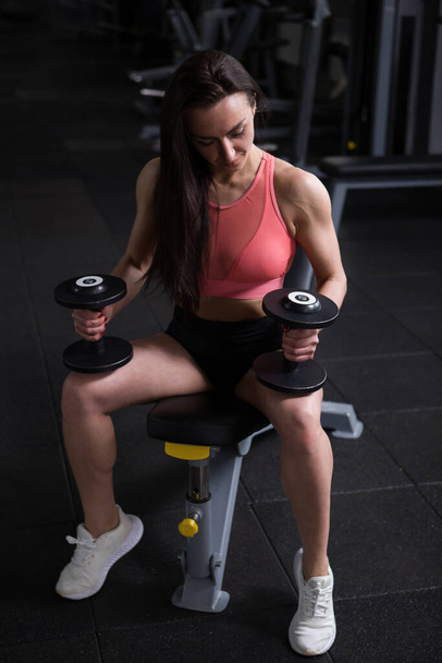 Tiro vertical completo de una mujer fisicoculturista haciendo ejercicio con pesas - Foto, imagen