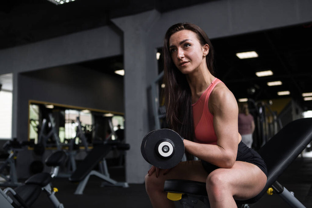 Femme sportive avec des bras musclés faisant des boucles biceps, à la salle de gym, espace de copie - Photo, image