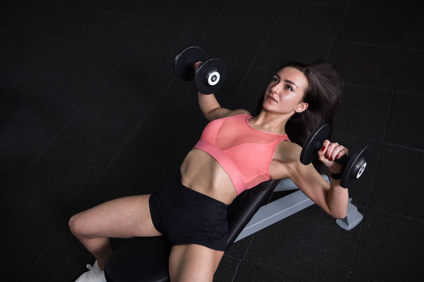 Top view shot of a female bodybuilder doing bench press with dumbbells - Fotó, kép