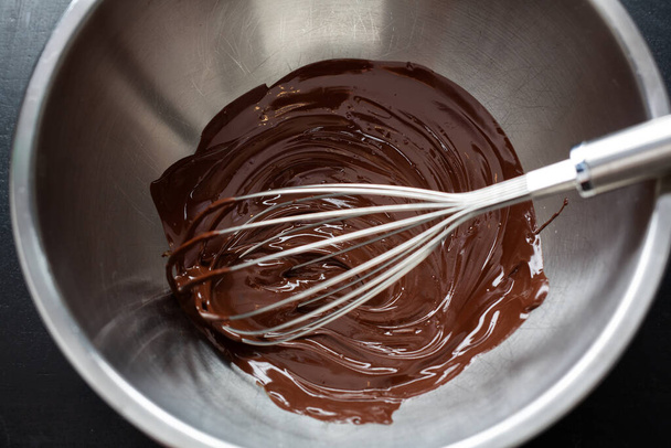 Melted chocolate in pot with chocolate pieces around on dark background. Top View.  - Photo, Image