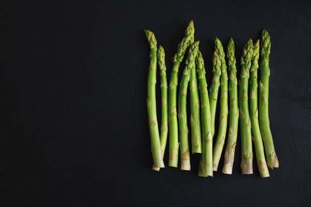 Green asparagus on dark background ready for cooking. View from above.  - Foto, Imagen