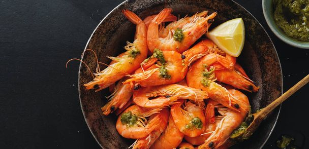 Tasty shrimps with spices and sauce on pan on dark background. Top View.  - Photo, image
