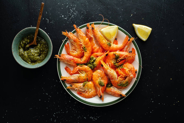 Tasty shrimps with spices and sauce on plate on dark background. Top View.  - Foto, Imagen