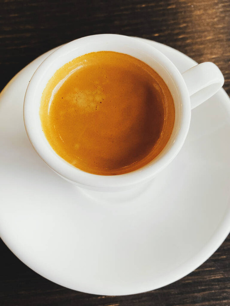 Tasty fresh italian espresso in white ceramic cup on table in cafe. Closeup  - 写真・画像