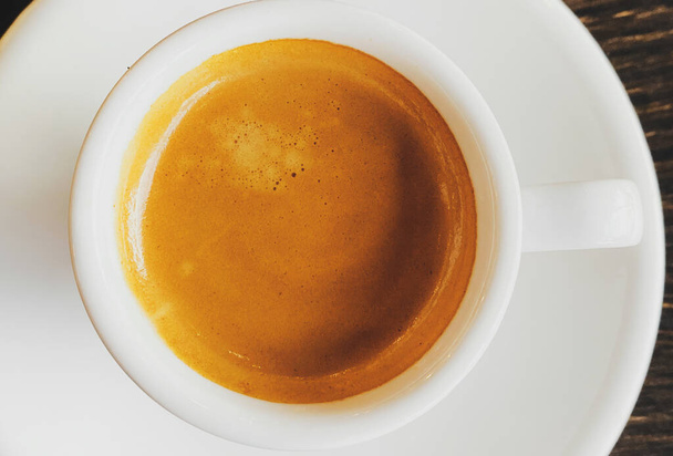 Tasty fresh italian espresso in white ceramic cup on table in cafe. Closeup  - Foto, Bild