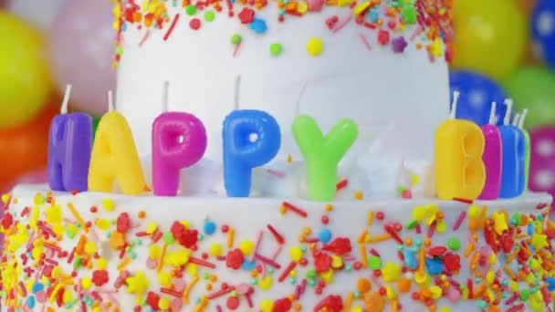 Tarta de cumpleaños con velas con globos de colores sobre fondo borroso - Metraje, vídeo