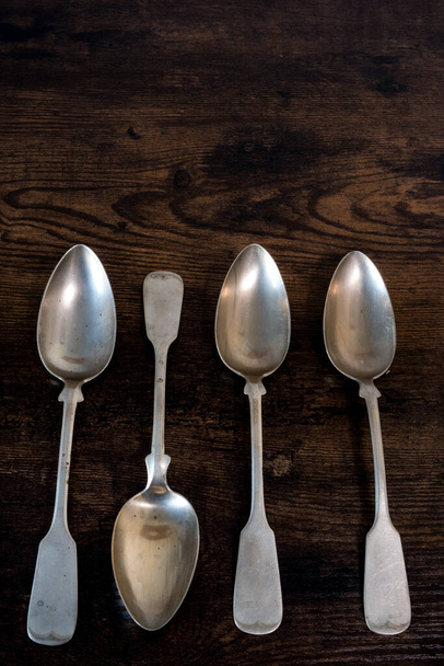 four spoons lie on a table while one lies the other way around - Φωτογραφία, εικόνα